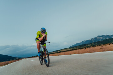 Full length portrait of an active triathlete in sportswear and with a protective helmet riding a...