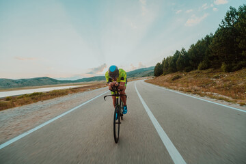 Full length portrait of an active triathlete in sportswear and with a protective helmet riding a...
