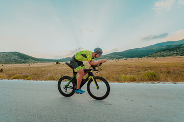 Full length portrait of an active triathlete in sportswear and with a protective helmet riding a...