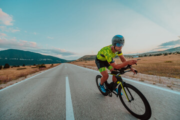 Full length portrait of an active triathlete in sportswear and with a protective helmet riding a...