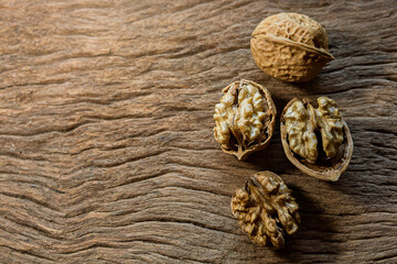 Raw brown organic walnut kernels with shell on rustic wooden table.