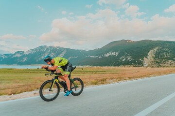 Full length portrait of an active triathlete in sportswear and with a protective helmet riding a...