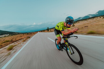 Obraz premium Full length portrait of an active triathlete in sportswear and with a protective helmet riding a bicycle. Selective focus 