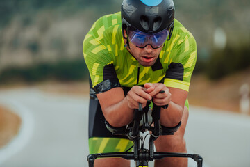 Close up photo of an active triathlete in sportswear and with a protective helmet riding a bicycle....