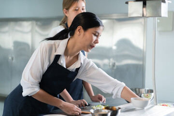 Cooking apprentices prepare meals and ingredients before the chef arrives to instruct at the culinary academy's kitchen.
