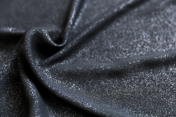 Black shimmering chiffon fabric with folds as texture background