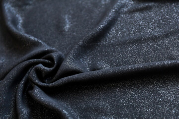 Black shimmering chiffon fabric with folds as texture background
