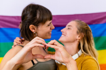 Two young lovers look into each other’s eyes and put their hands in the shape of hearts