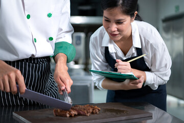 Student cooking apprentice Take notes on every step as the chef cooks in the culinary academy's...
