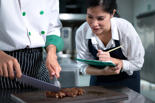 Student cooking apprentice Take notes on every step as the chef cooks in the culinary academy's kitchen.