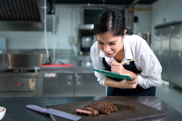 Portrait of student cooking apprentice Take notes on every step as the chef cooks in the culinary academy's kitchen.