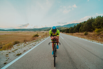 Full length portrait of an active triathlete in sportswear and with a protective helmet riding a...