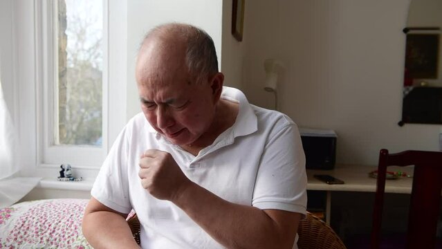 A elderly man coughing. Suffering the symptoms of Winter cold and flu.