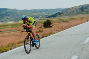 Fototapeta premium Full length portrait of an active triathlete in sportswear and with a protective helmet riding a bicycle. Selective focus 