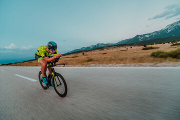 Full length portrait of an active triathlete in sportswear and with a protective helmet riding a bicycle. Selective focus 