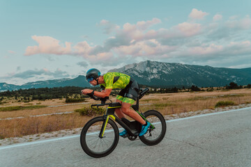 Naklejka premium Full length portrait of an active triathlete in sportswear and with a protective helmet riding a bicycle. Selective focus 