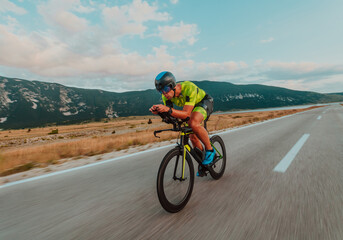 Full length portrait of an active triathlete in sportswear and with a protective helmet riding a bicycle. Selective focus 