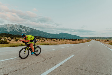 Full length portrait of an active triathlete in sportswear and with a protective helmet riding a...