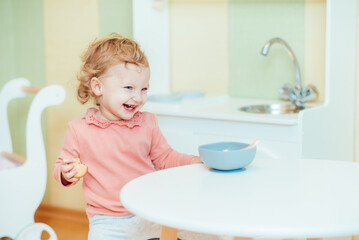 Happy little girl eating applesauce at home