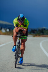 Full length portrait of an active triathlete in sportswear and with a protective helmet riding a bicycle. Selective focus 