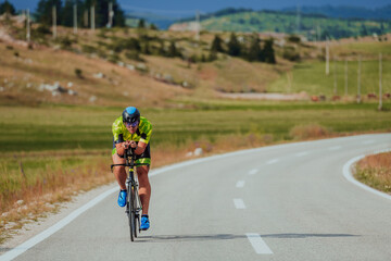 Full length portrait of an active triathlete in sportswear and with a protective helmet riding a...