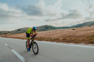 Full length portrait of an active triathlete in sportswear and with a protective helmet riding a...