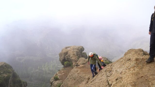 Hiking group ascending to Roque Nublo duroing a misty morning in Gran Canary Island, Spain.