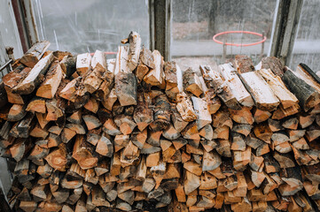 Chopped, sawn spruce firewood lies in a warehouse in a greenhouse for trees. Close-up photo.
