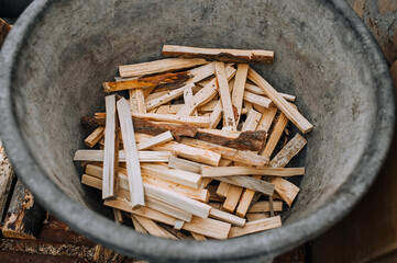 Chopped, sawn boards, firewood lie in a metal tank, bowl. Close-up photo, texture, top view.
