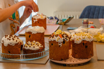 Boy decorating freshly baked homemade traditional Ukrainian Easter bread cake on the table