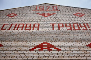 Socialist inscription in Russian on an apartment building. Glory to Labor 1970.