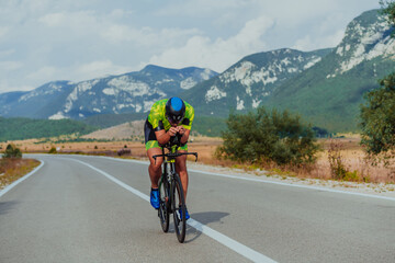 Fototapeta premium Full length portrait of an active triathlete in sportswear and with a protective helmet riding a bicycle. Selective focus 