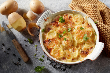 Hot delicious gratin potatoes with herbs in ceramic dish - 567365636
