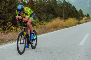 Full length portrait of an active triathlete in sportswear and with a protective helmet riding a...