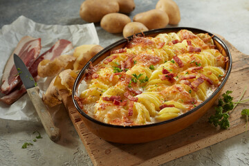 Yummy casserole with potato served with bacon slices and herbs