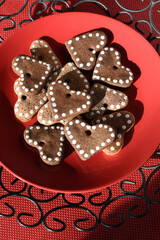 Plate with homemade heart shaped ginger cookies on a red background. Valentine's Day, Mother's Day treat. Love symbol.