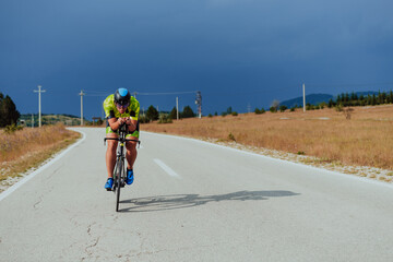 Full length portrait of an active triathlete in sportswear and with a protective helmet riding a...