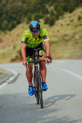 Full length portrait of an active triathlete in sportswear and with a protective helmet riding a bicycle. Selective focus 