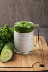 Chia seed pudding with curly kale, cucumber in glass on dark table. Healthy breakfast. Clean eating and superfoods concept. Vertical orientation.