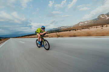 Full length portrait of an active triathlete in sportswear and with a protective helmet riding a...