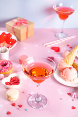 Romantic sweet dessert table with glass of pink wine, waffles, donut, ice cream, macaron, lollipop, candies. Valentine's day concept