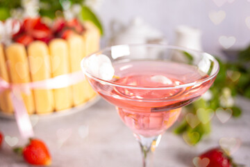 Glass of pink cocktail, cake with fresh strawberries with flowers branch of apple tree. Wedding or Valentines day romatic date couple concept.