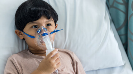 Sick boy inhalation therapy by the mask of inhaler. Baby has asthma and need nebulizations. Patient Boy use inhalation with Nebulizer mask at hospital. The baby are spraying bronchodilators .