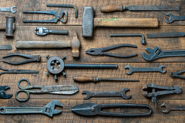 Vintage tools displayed on a background of wooden board, closeup, top view. Dirty set old working tools