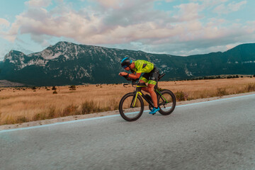 Full length portrait of an active triathlete in sportswear and with a protective helmet riding a...