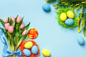 Greeting card Easter eggs flowers bouquet of tulips on a blue background with copy space.