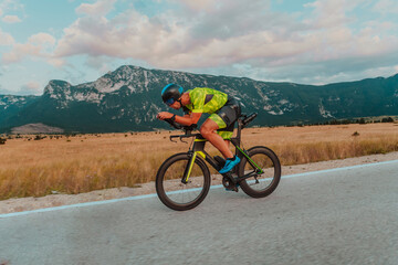 Obraz premium Full length portrait of an active triathlete in sportswear and with a protective helmet riding a bicycle. Selective focus 