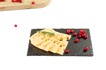 Cheese slices, rosemary and cranberries on a black stone kitchen board. Isolate on a white background