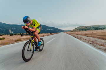 Full length portrait of an active triathlete in sportswear and with a protective helmet riding a...