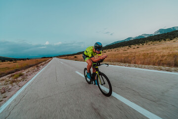 Full length portrait of an active triathlete in sportswear and with a protective helmet riding a bicycle. Selective focus 